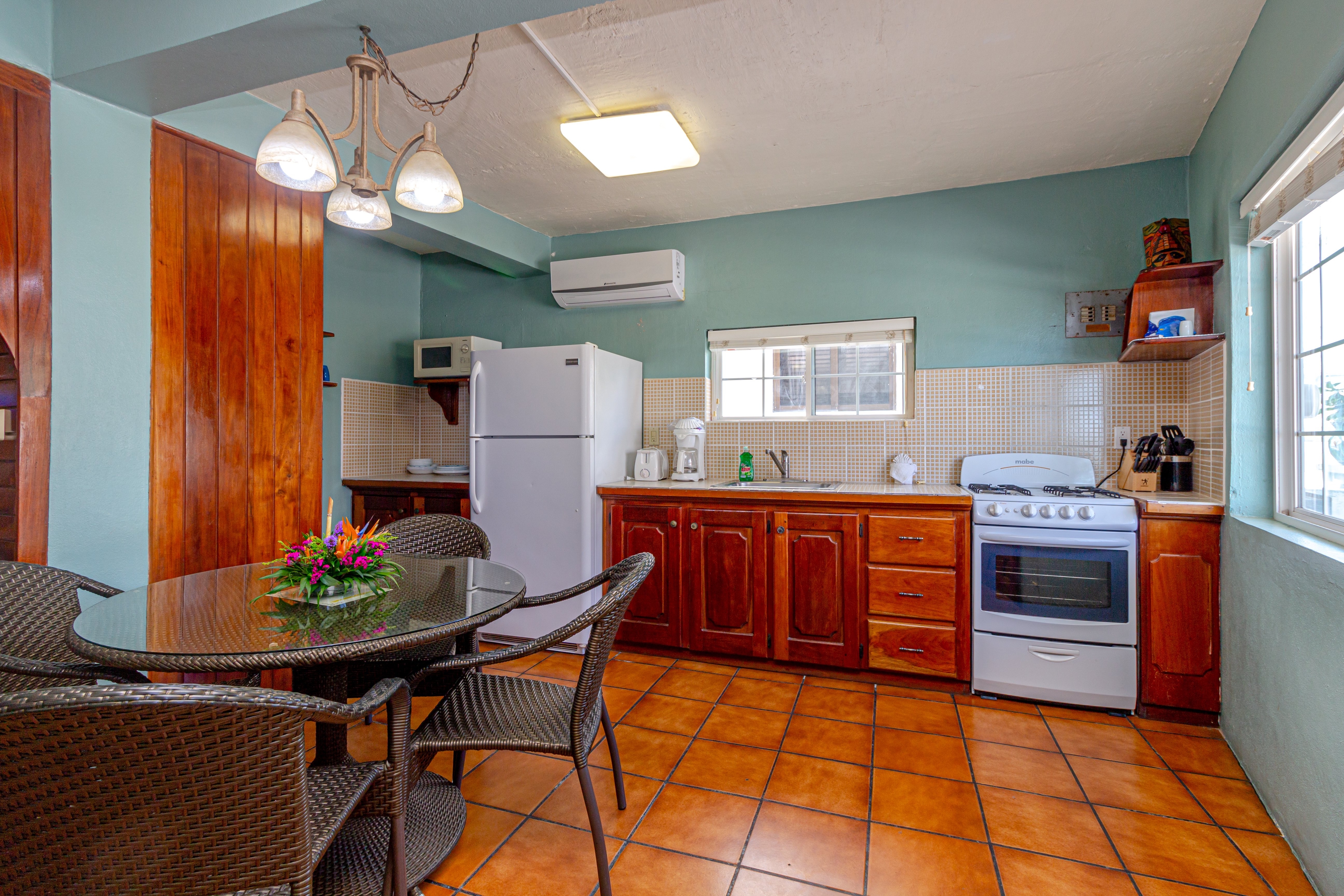 A dining area with a round table and chairs next to a compact kitchenette with white appliances and