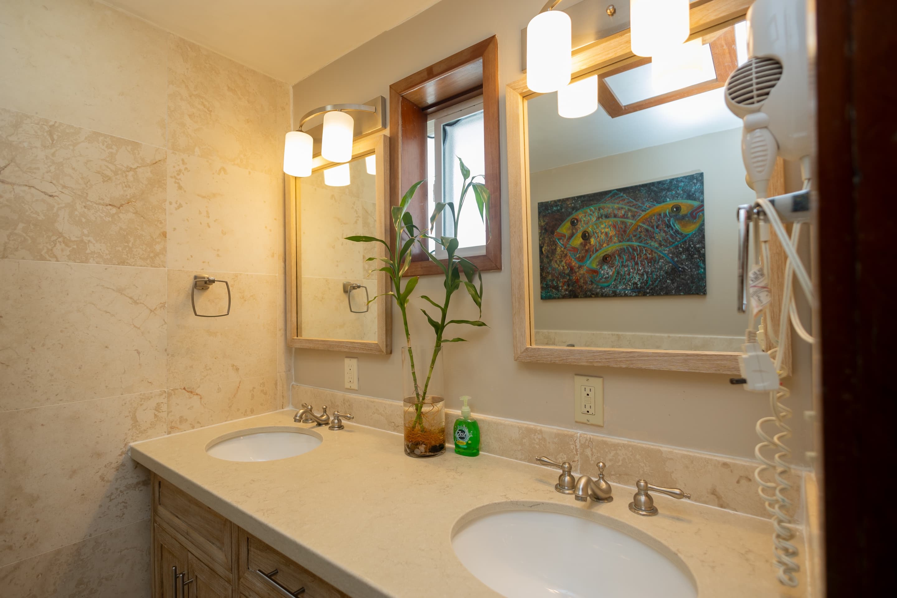 A bathroom featuring a double vanity with light countertops and white sinks, wooden-framed mirrors w