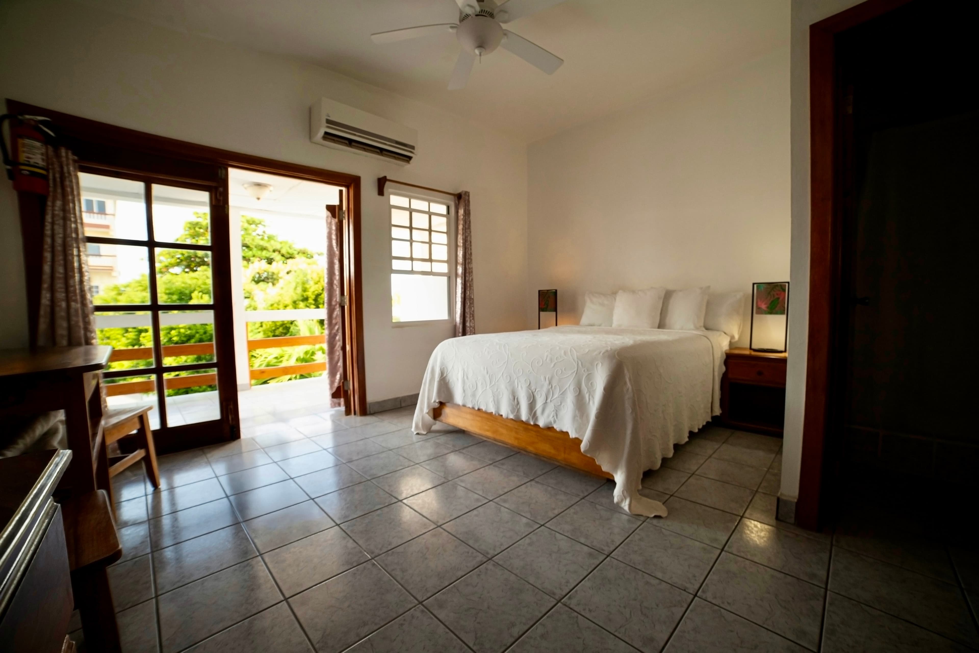 A well-lit room with a full-length mirror, a flat-screen TV mounted on the wall, a wooden desk with