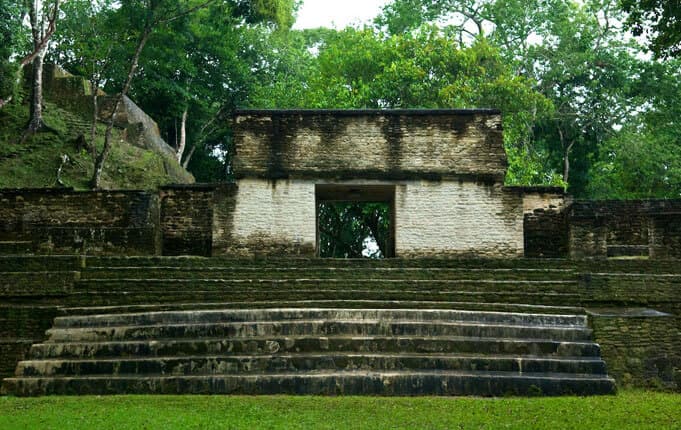 Ancient stone structure with steps surrounded by lush greenery.