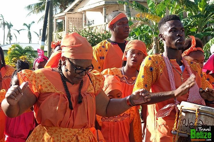 A group of individuals in vibrant orange clothing dances together during a cultural celebration.