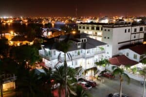A nighttime view of a cityscape featuring illuminated buildings and palm trees.