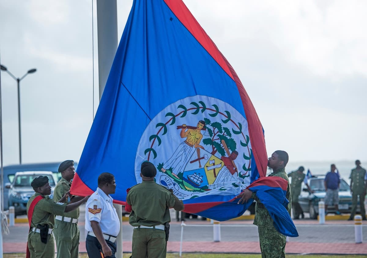 A group of soldiers and officials are raising the flag of Belize during a ceremony. A group of soldiers and officials are raising the flag of Belize during a ceremony.