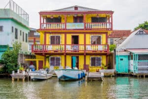 Colorful two-story house by the water with boats moored in front.